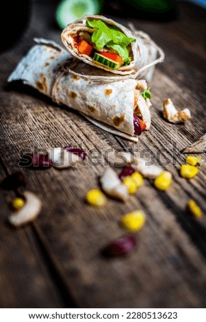 Traditional mexican tortilla wrap with chicken meat and vegetables on wood table