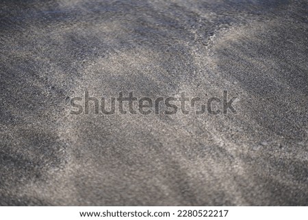 Sand patterns and ocean water over the beach of white and black sand