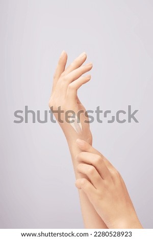 Beautiful woman's hand applying cream on back of hand, applying lotion on skin. Close-up in light background. Skin care concept, try anti-irritant cream Royalty-Free Stock Photo #2280528923