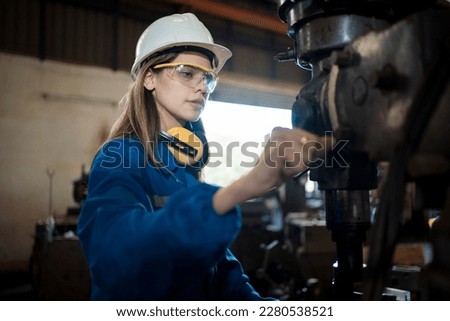 Woman worker operating a machine tool in metal factory. Royalty-Free Stock Photo #2280538521