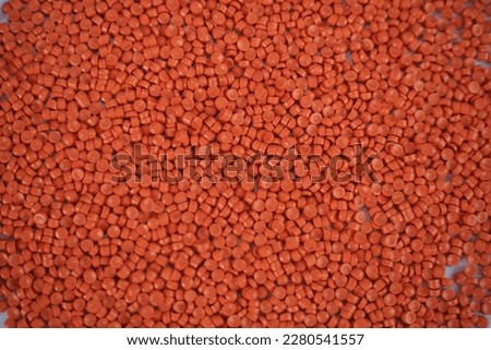 Close-up of orange plastic polymer granules. polymer plastic. compound polymer. PVC resin compounds. Tinted plastic granulate for injection moulding process. Royalty-Free Stock Photo #2280541557