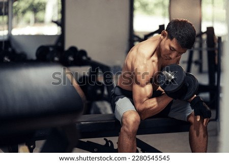 Asian man shirtless workout weight training biceps muscles with dumbbell in fitness gym. Weight training exercise in concept of health and wellness. Royalty-Free Stock Photo #2280545545