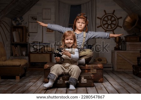 Children play in the attic of their house. Imagine themselves as tourists, explorers. Look through a telescope, study a world map, play in a makeshift tourist tent. Dreaming of travel and adventure. Royalty-Free Stock Photo #2280547867