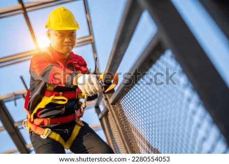 A worker working at height equipment. Fall arrestor device for worker with hooks for safety body harness on the roof structure. Safety body construction. selective focus of hook safety body harness.  Royalty-Free Stock Photo #2280554053