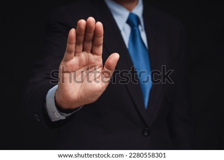 A businessman in a suit shows a stop gesture while standing on a black background. Space for text. Close-up photo Royalty-Free Stock Photo #2280558301