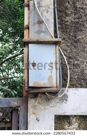 View of old and rusty electricity control and distribution metal cabinet hanged on wall. No people.