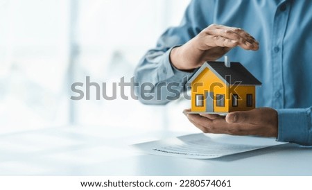 Broker agent with model toy house with documents signed purchase and sale contracts and mortgages including fire insurance