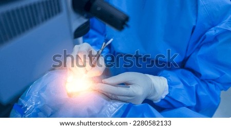 Surgeon or doctor in blue uniform did microsurgery inside operating room with light effect.Eye surgery or brain surgery in theater.Plastic and cosmetic surgery under medical technology.People working. Royalty-Free Stock Photo #2280582133