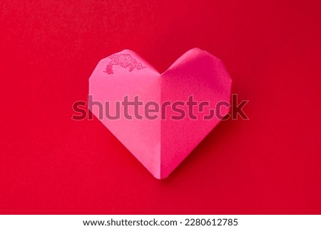 Pink paper heart origami isolated on a blank red background. Valentines day card