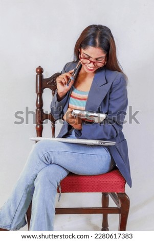 Happy young indian student with laptop, notebook and pen, smiling hindu female professional, teenager student siting on chair with laptop