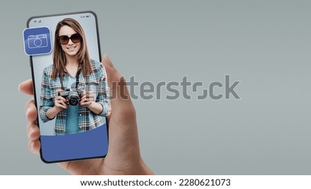 Photographer holding a camera on smartphone screen, online professional services concept