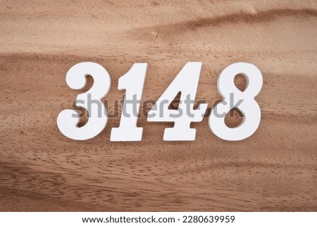 White number 3148 on a brown and light brown wooden background.
