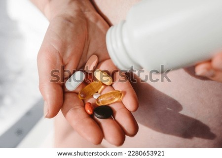 Closeup photo of supplements with a white bottle. Pregnant woman take omega 3, multivitamins, vitamins B, C, D, collagen tablets, probiotics, iron capsule. Girl hold vitamins daily. Top view. Royalty-Free Stock Photo #2280653921