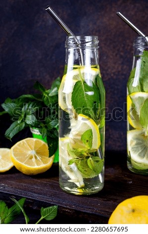 Fresh mojito cocktail drinks in bottles and ingredients, lemon and mint eaves in bascet on dark background, cocktail summer drinks concept 
