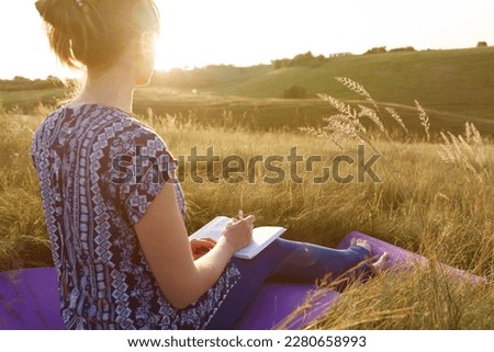 a girl sits in a field at sunset, self-knowledge, self-development, enjoy nature, the landscape with the high mountains, #uniquesself

 Royalty-Free Stock Photo #2280658993