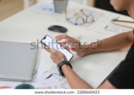 Side view of young creative man in casual clothes using smart phone at workstation