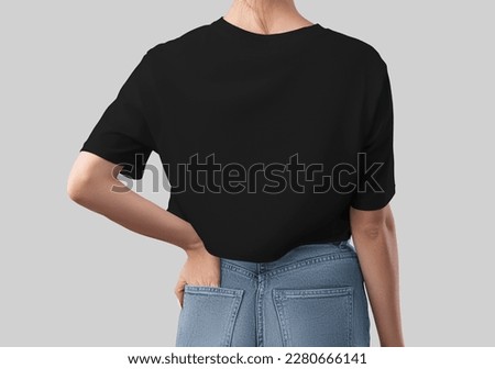 Mockup of black crop top on girl with hand in pocket, back view, fashionable female canvas bella shirt, for design, branding, advertising. T-shirt template closeup, apparel isolated on background