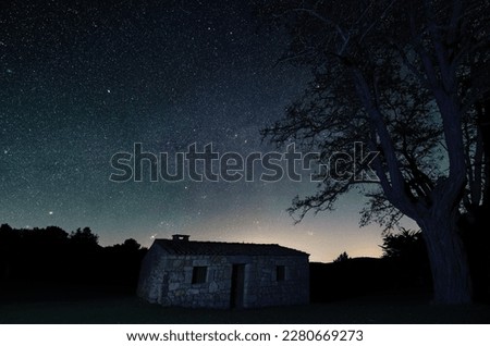 Long Exposure night photograph with stars in the background and foreground a house and a tree
