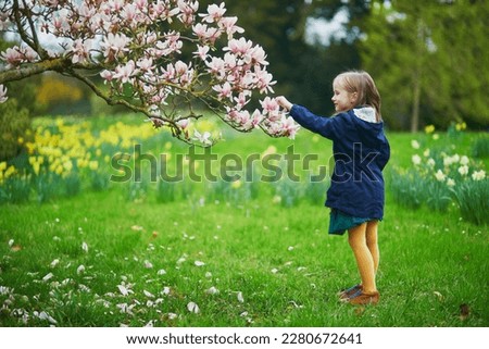 Adorable preschooler girl enjoying nice spring day in park during magnolia blooming season. Outdoor springtime activities for kids. Little child exploring nature