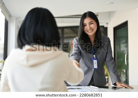 Attractive and charming millennial Asian businesswoman or female banker shaking hand with her business client in the office. Royalty-Free Stock Photo #2280682851