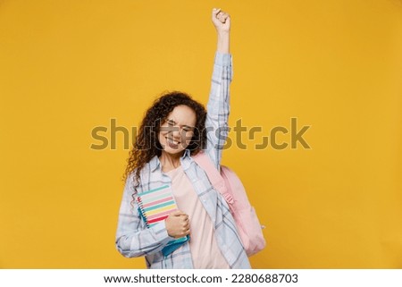Young fun black teen girl student she wear casual clothes backpack bag hold books do winner gesture celebrate say yes isolated on plain yellow color background. High school university college concept Royalty-Free Stock Photo #2280688703