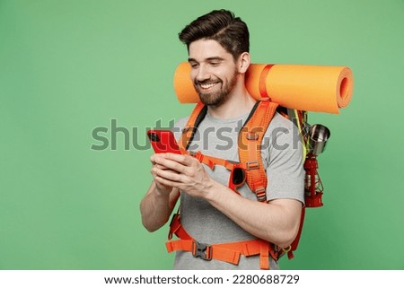 Young fun traveler white man carry backpack stuff mat use mobile phone isolated on plain green background Tourist leads active healthy lifestyle walk on spare time Hiking trek rest travel trip concept Royalty-Free Stock Photo #2280688729