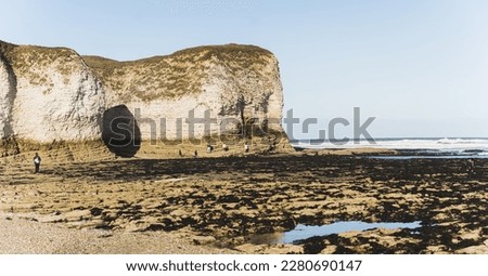 Flamborough Head beach. North Landing beach - beautiful expanse of sand, white pebbles and rock pools. Tourists' silhouettes. High quality photo