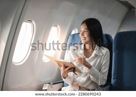 Asian young woman take notes in a notebook sitting near windows at first class on airplane during flight,Traveling and Business concept Royalty-Free Stock Photo #2280690243