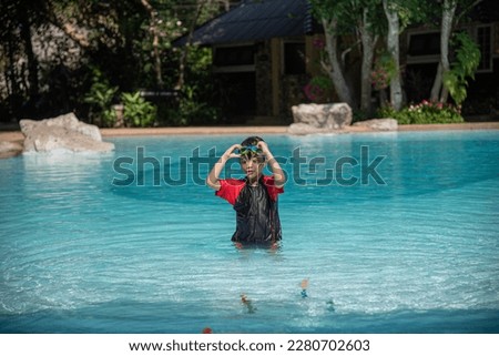 Asian little girl in swimsuit playing with toys at swimming pool happily and having fun.