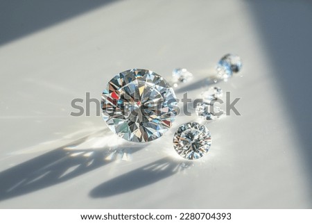 Close up of diamonds of different cuts and sizes on light background with shadows. Royalty-Free Stock Photo #2280704393