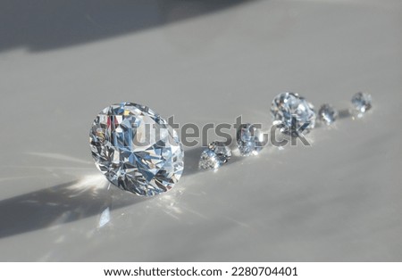Close up of diamonds of different cuts and sizes on light background with shadows. Royalty-Free Stock Photo #2280704401