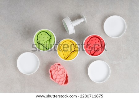 Colorful dough in white jars on gray background. Flat lay