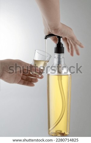 Close-up shot of dispenser pressing woman's hand while squeezing syrup toppings into clear glass