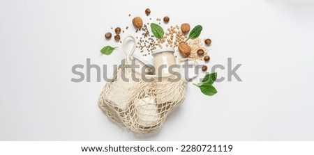 Variety of vegan plant based milk in zero waste mesh bag. Top view of lactose free milk based on nuts, legumes, oatmeal on white background Royalty-Free Stock Photo #2280721119