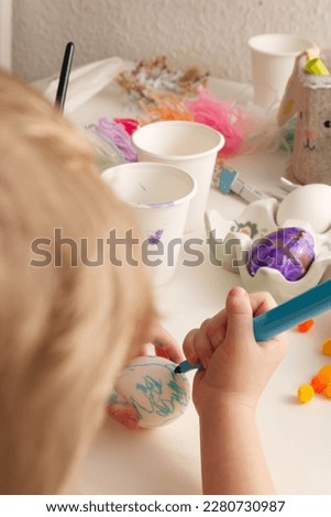Children's hands paint Easter eggs with elements of spring decor table top view. High quality photo