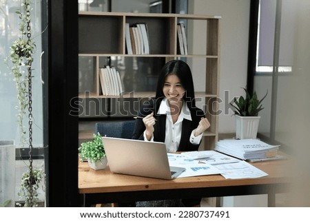 Asian businesswoman raising hands happily with successful plan with happy smile with laptop computer.