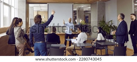 Group of adult students having class with business teacher in modern office interior. Man raises his hand to answer question, ask something or make interesting suggestion. Team training concept banner