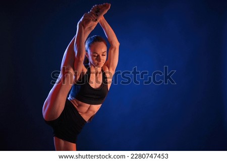 Fitness exercises. Beautiful muscular woman is indoors in the studio with neon lighting.