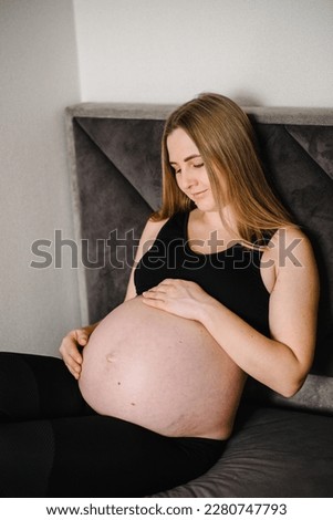 Pregnant woman. Pregnancy, motherhood, procreation concept. Closeup belly of woman. Female waiting for newborn baby. Young pregnant girl touching and holding her belly and caring about health indoors.