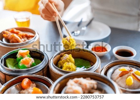 Young woman traveler eating traditional Chinese Dim Sum at restaurant Royalty-Free Stock Photo #2280753757