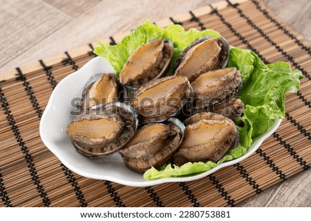 Delicious raw abalone in a plate with lettuce on wooden table background. Royalty-Free Stock Photo #2280753881