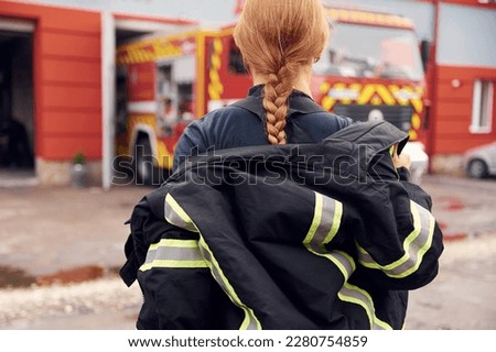 Taking off the protective clothes. Woman firefighter in uniform is at work in department.