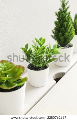 Artificial plants on table near light wall