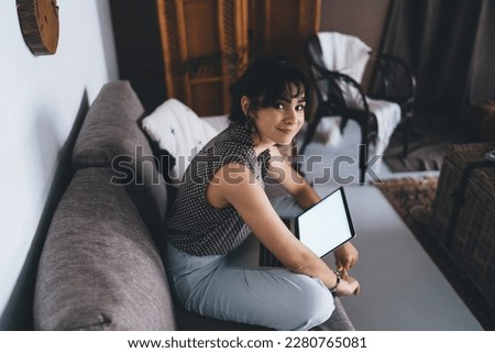 Young female sitting front open laptop computer with blank mock up screen for paste advertising content or web design. Woman freelancer working distantly on netbook. Student learning via online course