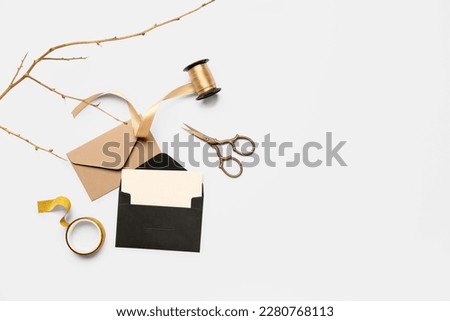 Composition with envelopes, blank card, scissors and ribbon on white background