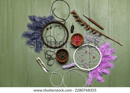 Materials for making dream catchers on green wooden background