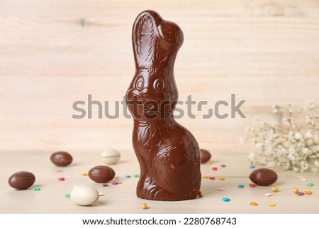 Chocolate Easter bunny with eggs and sprinkles on light wooden background Royalty-Free Stock Photo #2280768743