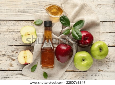Glass bottle and gravy boat with fresh apple cider vinegar on white wooden background Royalty-Free Stock Photo #2280768849