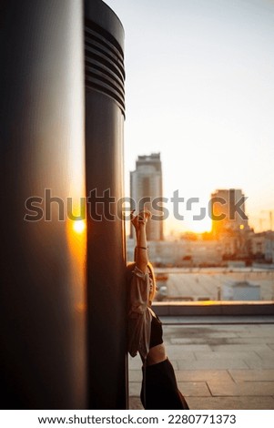 Photo shoot on the roof. Young woman posing in the roof at sunset. Fashion, style concept.