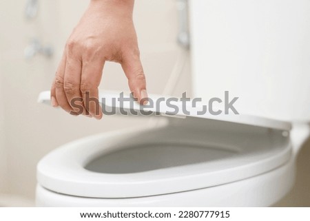 close up hand of a woman closing the lid of a toilet seat. Hygiene and health care concept. Royalty-Free Stock Photo #2280777915